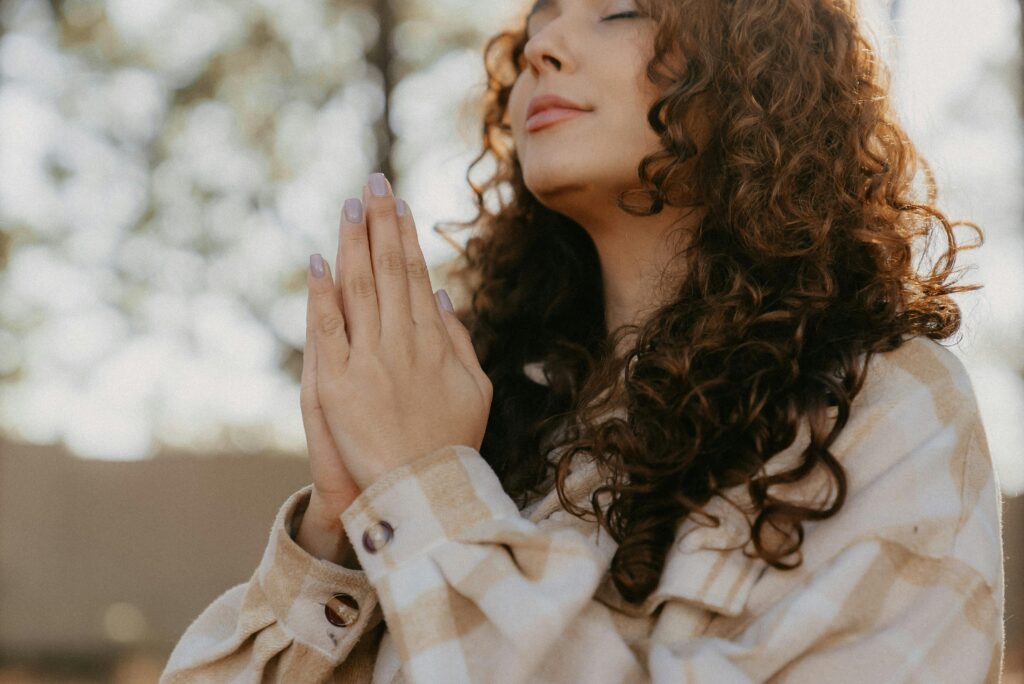 Girl with a serene look on her face showing the power of gratitude with her hands in prayer