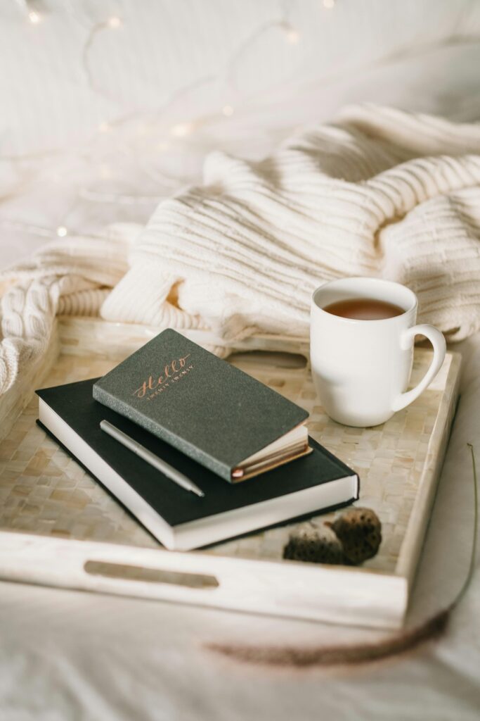 Relaxing setup with a cup of tea and journal on a bed, perfect for a cozy winter afternoon.