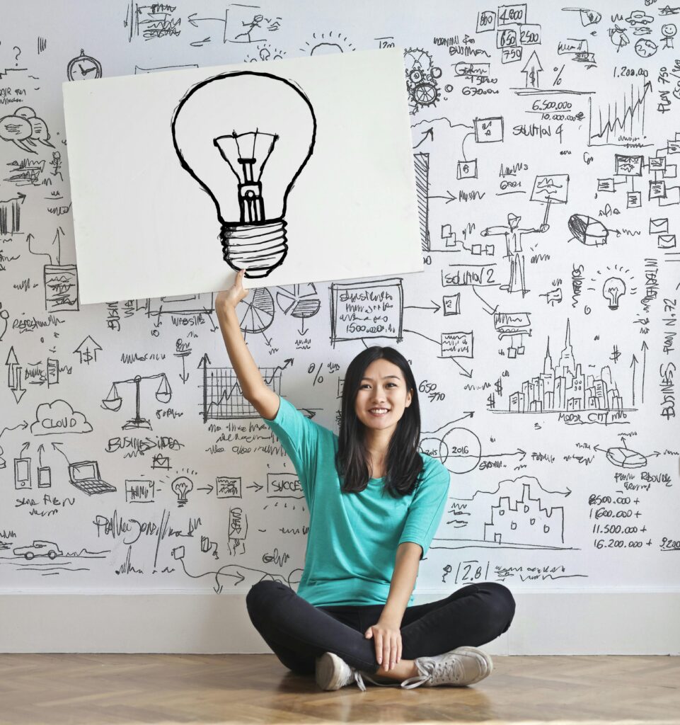 pexels-photo-3758105-3758105 Young woman holds a light bulb drawing against a creative brainstorming wall to help achieve mental focus