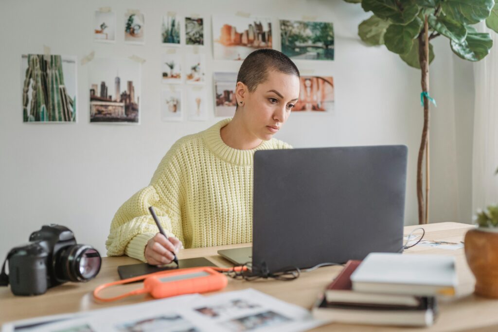 pexels-photo-7014916-7014916 Young woman sitting at a desk, focused while using an iPad for digital planning