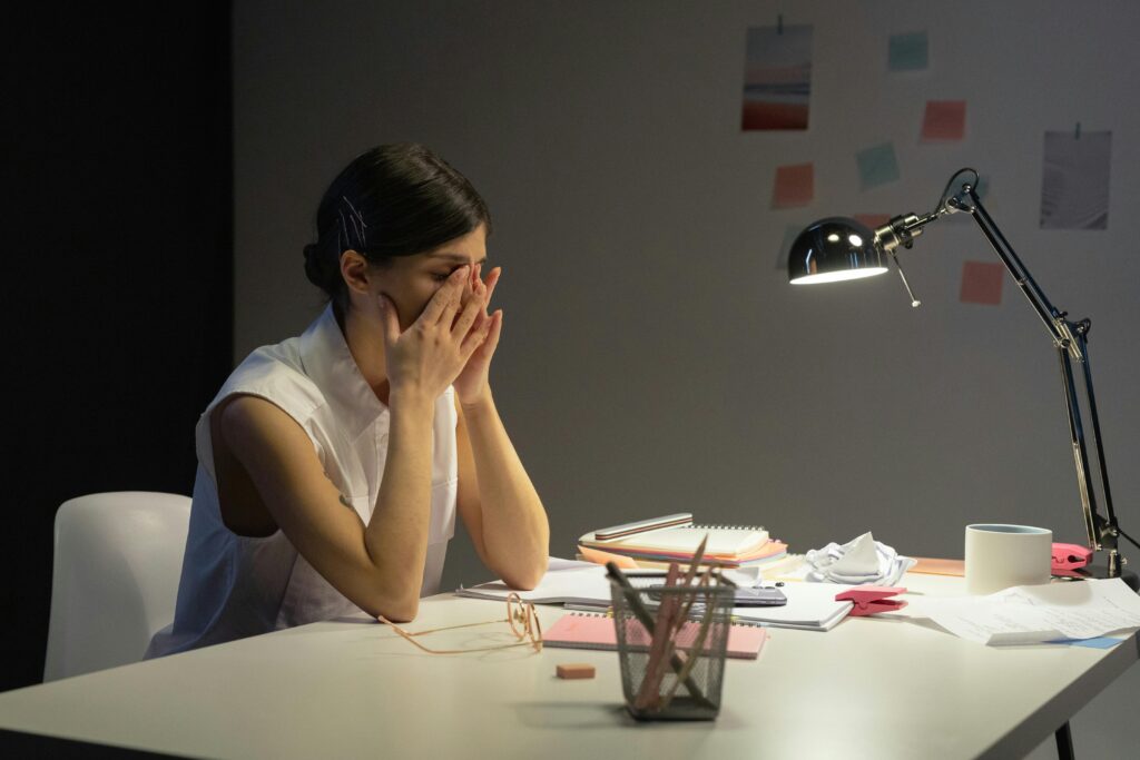 pexels-photo-9063397-9063397 A stressed businesswoman rubs her eyes at a cluttered desk, overwhelmed by work.