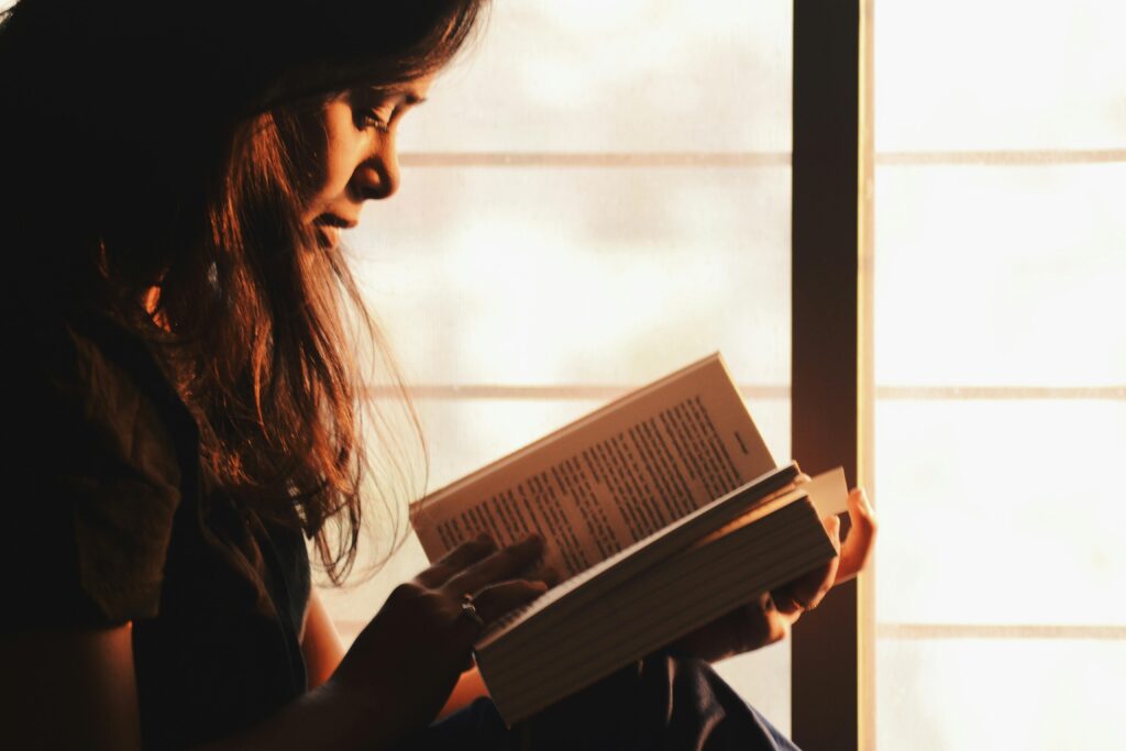 pexels-photo-1031588-1031588 A woman engrossed in reading a book by a sunlit window creates a serene atmosphere. living a slow life